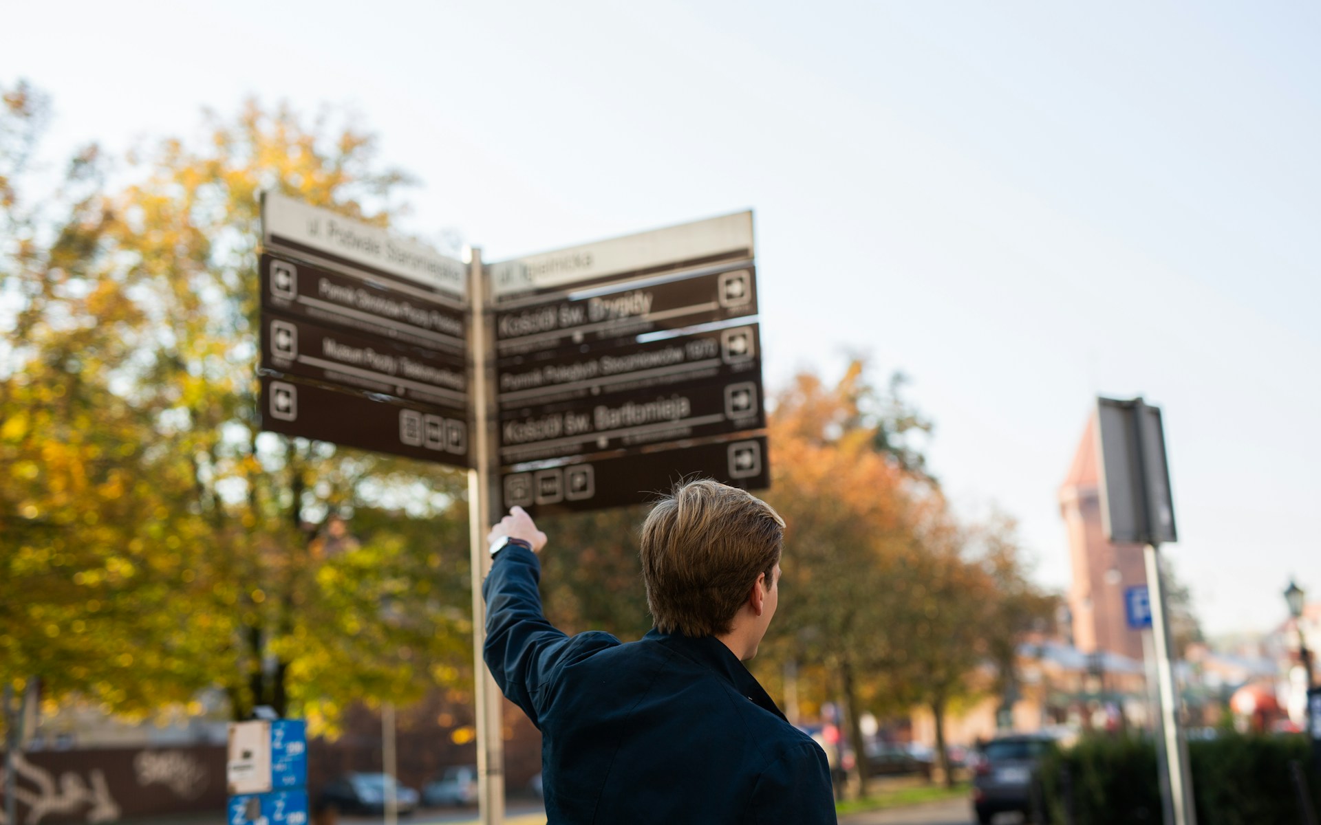 Man in black suit jacket near road sign