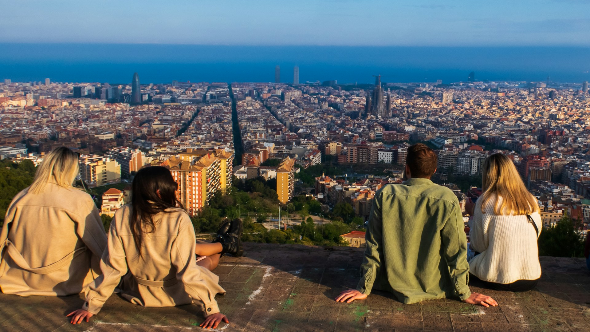 A group of people sitting together on a ledge overlooking a city