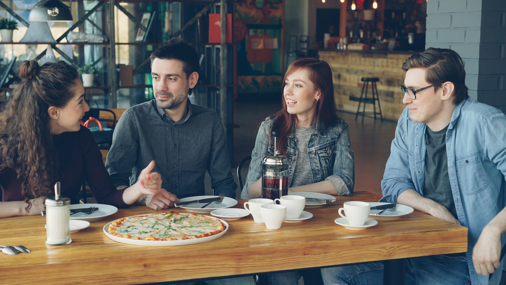 Friends talking and sharing food at a restaurant table