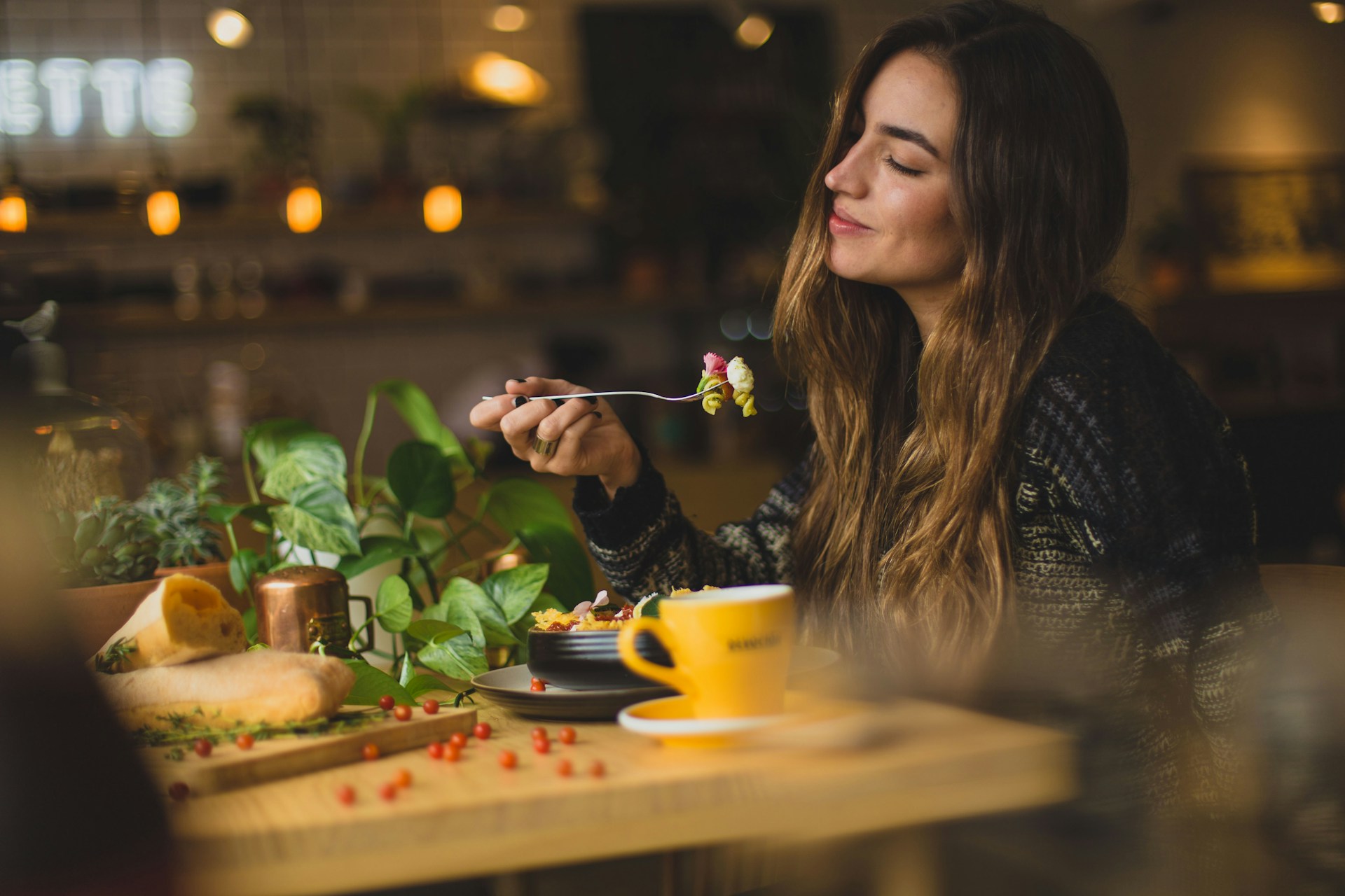 A woman holding a fork in front of a table in a restaurant